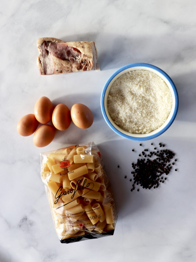 Ingredients for making a traditional carbonara pasta placed on a marble background. 